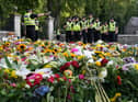 Police officers arrive at the gates of Balmoral in Scotland where flowers and tributes have been laid by members of the public following the death of Queen Elizabeth II. The Queen's coffin will be transported on a six-hour journey from Balmoral to the Palace of Holyroodhouse in Edinburgh, where it will lie at rest. Picture date: Sunday September 11, 2022.