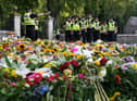 Police officers arrive at the gates of Balmoral in Scotland where flowers and tributes have been laid by members of the public following the death of Queen Elizabeth II. The Queen's coffin will be transported on a six-hour journey from Balmoral to the Palace of Holyroodhouse in Edinburgh, where it will lie at rest. Picture date: Sunday September 11, 2022.