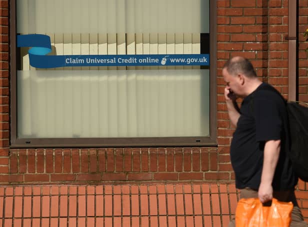 <p>A man walks past a sign with the email address of ‘universal credit’ outside a Job Centre.</p>