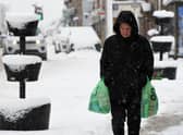 A pedestrian carries their shopping through the snow in Auchterarder, central Scotland, on February 18, 2022, as Storm Eunice brings high winds across the country.
