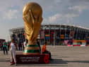 People pose for photos next to a giant replica on the World Cup trophy in front of Stadium 974 on November 18, 2022 in Doha, Qatar