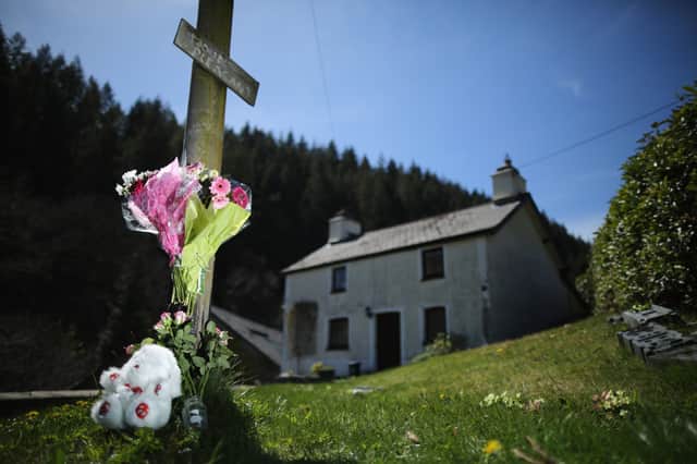 A teddy bear and floral tributes adorn a post outside of the former home of Mark Bridger in Ceinws.