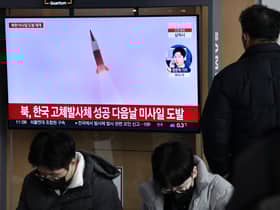 A man watches a television screen showing a news broadcast with file footage of a North Korean missile test, at a railway station in Seoul on December 31, 2022
