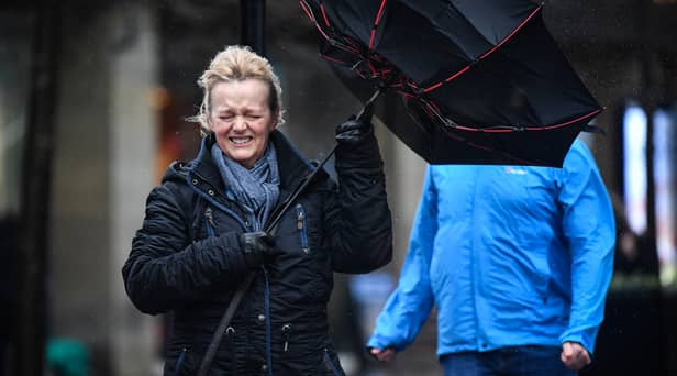 A woman battles to keep control of her umbrella as she walks through a rain shower in Glasgow.