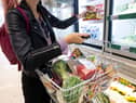 A woman holds a basket of shopping.