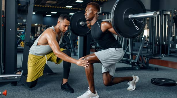 Man with his trainer in gym (Adobe)