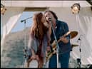 Riley Keough as Daisy Jones and Sam Claflin as Billy Dunne in Daisy Jones & The Six, singing into a shared microphone (Credit: Lacey Terrell/Prime Video)