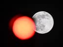 TOPSHOT - This picture taken on February 5, 2023 shows the full moon rising behind a red crossing light in Paris. (Photo by Stefano RELLANDINI / AFP) (Photo by STEFANO RELLANDINI/AFP via Getty Images)