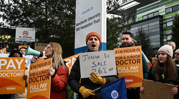 Demonstrators hold placards as they take part in a protest by junior doctors, amid a dispute with the government over pay, outside of Saint Mary's Hospital, in Manchester, on March 15, 2023. 
