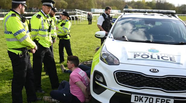 An animal rights protester is apprehended by police officers ahead of the Grand National. 