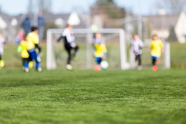 Blur of young kids playing a youth soccer match outdoors on an green soccer pitch.