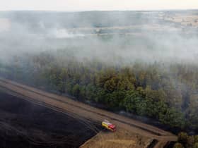 In this aerial view, a fire engine is seen on the field while smoke rises from the trees on July 19, 2022 in Blidworth, England