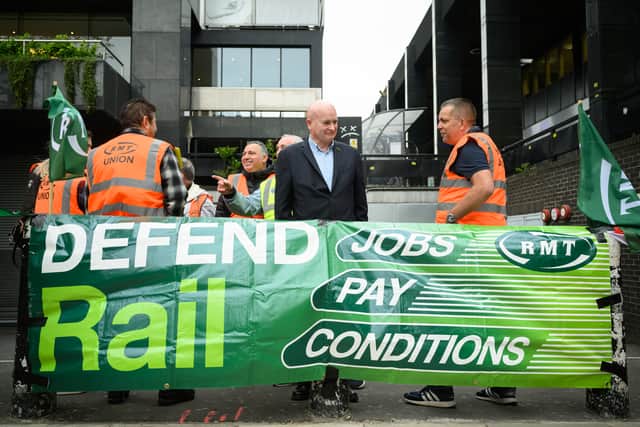 Secretary-General of the National Union of Rail, Maritime and Transport Workers (RMT) Mick Lynch (C) stands with union members at a picket line outside Euston Station.