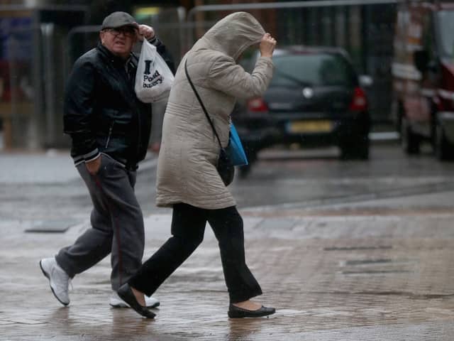 People walk in rain and high winds.