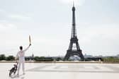 Torch bearer Matthias Dandois, French bicycle rider, poses for a photo with the Olympic Torch with the Eiffel Tower in view (Photo: Maja Hitij/Getty Images)