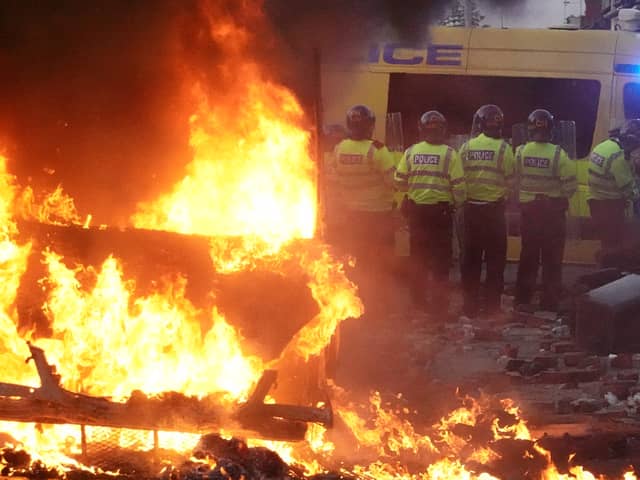 Riot police hold back protesters near a burning police vehicle after disorder broke out on July 30, 2024 in Southport, England. Rumours about the identity of the 17-year-old suspect in yesterday's deadly stabbing attack here have sparked a violent protest. According to authorities and media reports, the suspect was born in Cardiff to Rwandan parents, but the person cannot be named due to his age. A false report had circulated online that the suspect was a recent immigrant who crossed the English Channel last week and was "on an MI6 watchlist." 