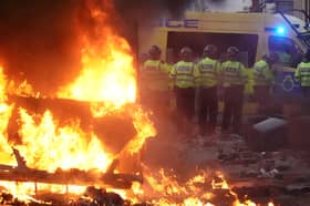 Riot police hold back protesters near a burning police vehicle after disorder broke out on July 30, 2024 in Southport, England. Rumours about the identity of the 17-year-old suspect in yesterday's deadly stabbing attack here have sparked a violent protest. According to authorities and media reports, the suspect was born in Cardiff to Rwandan parents, but the person cannot be named due to his age. A false report had circulated online that the suspect was a recent immigrant who crossed the English Channel last week and was "on an MI6 watchlist." 