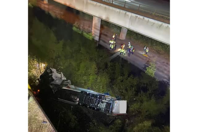 Cheshire Fire and Rescue Service photo of emergency services on the scene under a bridge on the M6 in Cheshire where a lorry fell 60 metres from the Thelwall Viaduct between junctions 20 and 21, landing on the embankment below. Monday September 30, 2024.