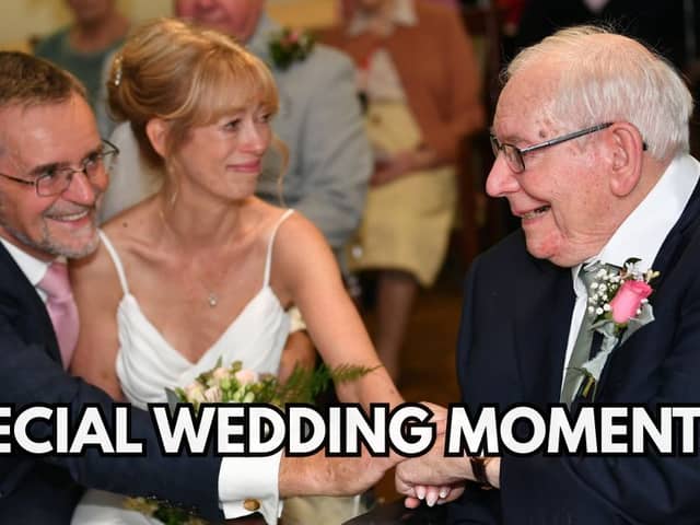 A couple on their wedding day clasping hands with the bride's father