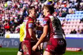 Jai Field (left) and Sam Walters (right) celebrate a Wigan Warriors try