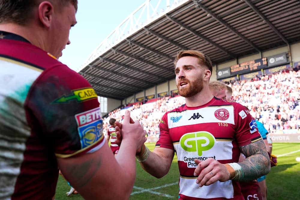 Adam Keighran celebrates a Wigan Warriors win with teammate Harvie Hill