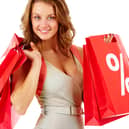A shopper carrying red sale bags marked with a bold percentage sign, symbolising seasonal discounts and bargain hunting