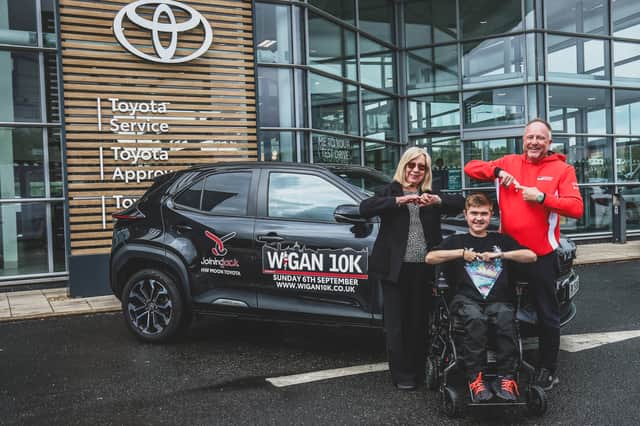 Jack Johnson does the "Joining Jack salute" as he receives the keys to the Wigan 10k lead car from Steve Mather, centre principal, and Dorothy Moon, managing director, at HW Moon Toyota. Picture: Michelle Charnock Photographer