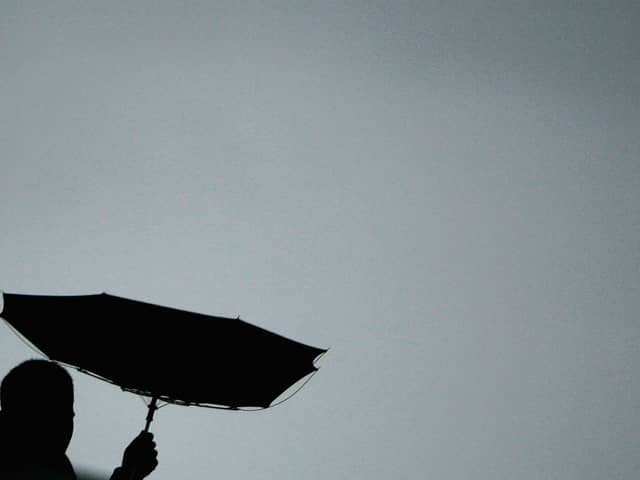A pedestrian struggles with the elements as he walks along the river in London.