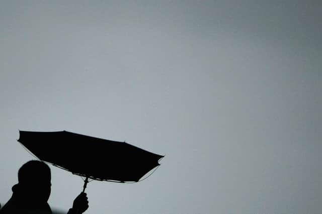 A pedestrian struggles with the elements as he walks along the river in London.