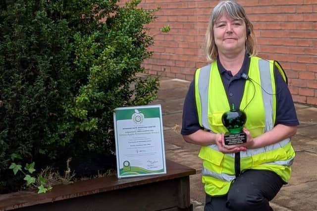 A member of the cleaning team, Brenda Sharrock, proudly shows previous Green Apple awards