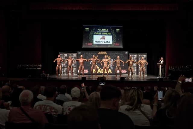 The audience watches the First Timers class at a NABBA North West show in 2025.