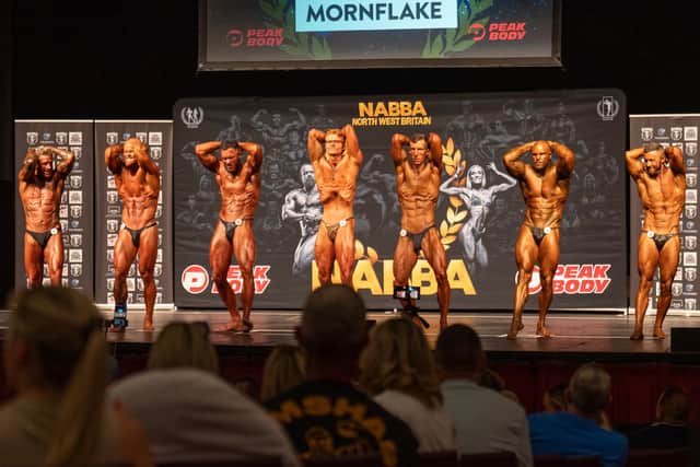 Bodybuilders pose on stage at a NABBA North West show in 2025.