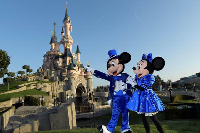 Disney characters Mickey and Mini mouse pose in front of the Sleeping Beauty Castle (BERTRAND GUAY/AFP via Getty Images)