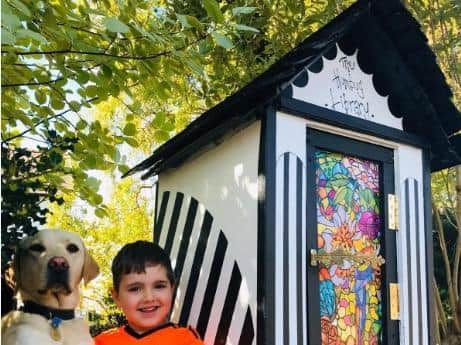 Five-year-old Woodfield Primary School pupil Maxwell and the familys guide dog in training Loki with the new little library constructed from spare objects