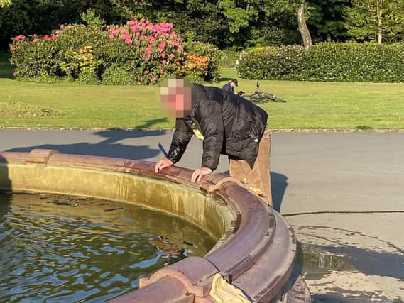 The man, broom at his side, looks into the water. Picture taken by Mark Baxter