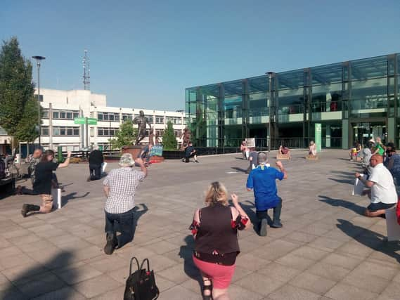 Campaigners kneeling in front of the Billy Boston statue