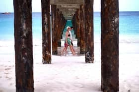 Two tourist walk under a jetty as they stroll along a beach in Bridgetown, Barbados