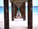 Two tourist walk under a jetty as they stroll along a beach in Bridgetown, Barbados