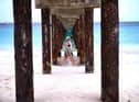 Two tourist walk under a jetty as they stroll along a beach in Bridgetown, Barbados
