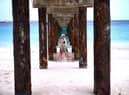 Two tourist walk under a jetty as they stroll along a beach in Bridgetown, Barbados