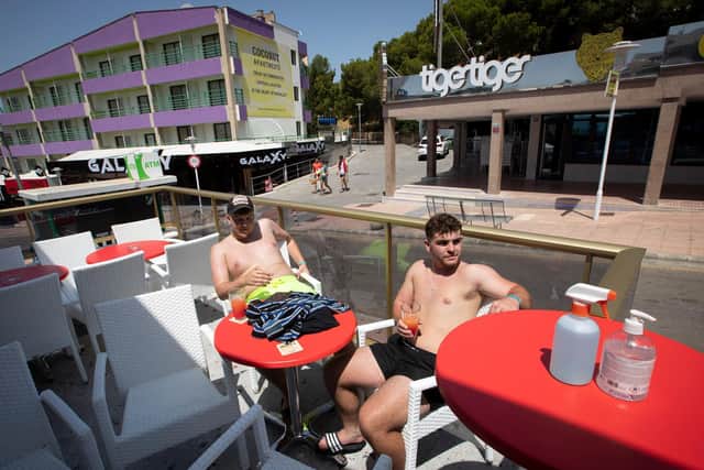 Two tourists sit at a bar on Punta Ballena street in Magaluf on the Spanish island of Mallorca (Photo by JAIME REINA/AFP via Getty Images)