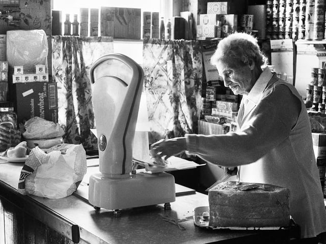 Janie Geller weighs out some boiled ham for a customer in her grocery shop in Up Holland Road, Billinge, in 1988.