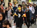 Pedestrians, some wearing a face mask or covering due to the COVID-19 pandemic, walk in Manchester