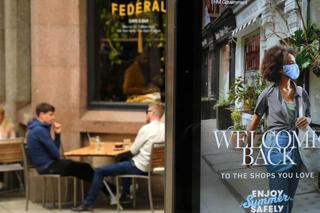 Customers sit outside a bar, near a sign promoting post-COVID-19 lockdown shopping, in Manchester
