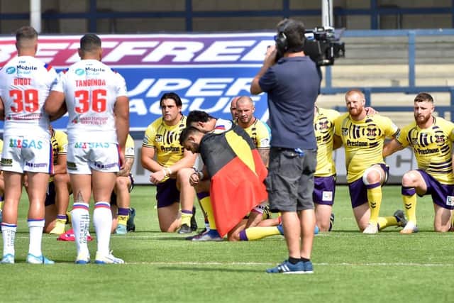 Bevan French and David Fifita take a knee for Black Lives Matter with the Australia Aboriginal flag draped over their backs