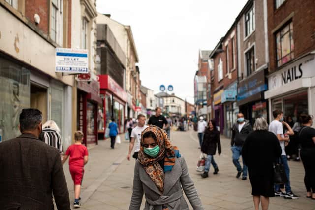 Pedestrians wear facemasks as they walk through a pedestriansed street in Oldham, Greater Manchester (Photo by OLI SCARFF/AFP via Getty Images)