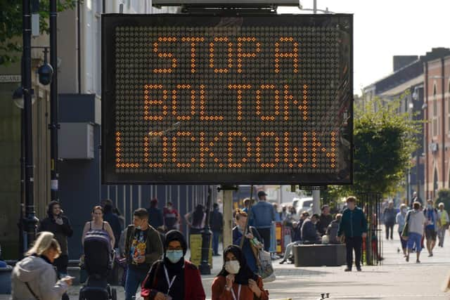 People walk past an electronic sign displaying health advice about COVID-19 in Bolton (Photo by Christopher Furlong/Getty Images)