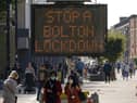 People walk past an electronic sign displaying health advice about COVID-19 in Bolton (Photo by Christopher Furlong/Getty Images)
