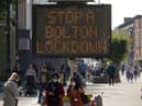 People walk past an electronic sign displaying health advice about COVID-19 in Bolton (Photo by Christopher Furlong/Getty Images)