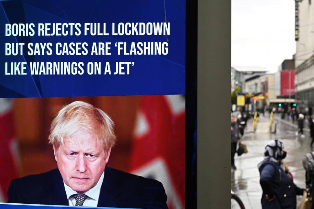 A news display features Britain's Prime Minister Boris Johnson as shoppers make their way along the streets of Manchester